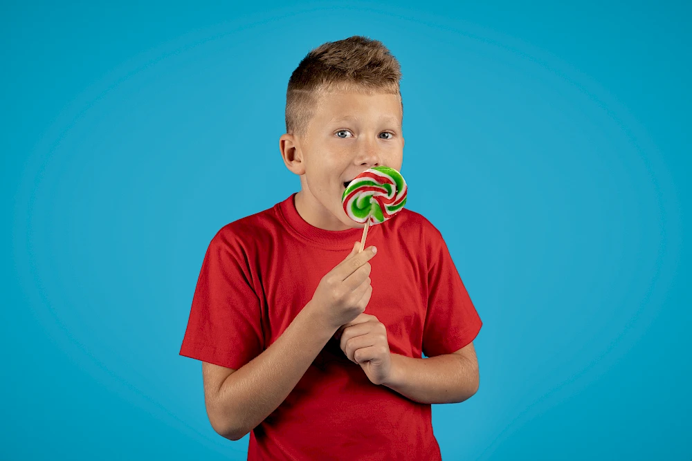 Jonge tiener die lekt aan zijn kleurrijke lolly.
